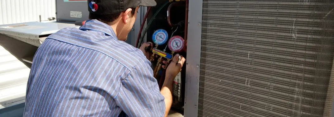 HVAC technician servicing a condenser unit in Badger