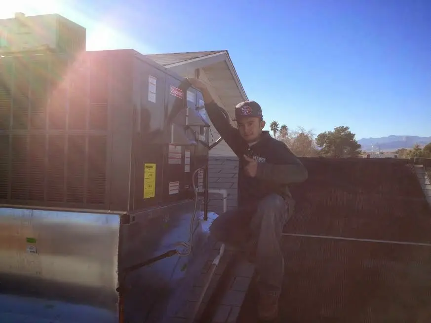HVAC technician performing AC Tune-Up on a rooftop unit in Badger